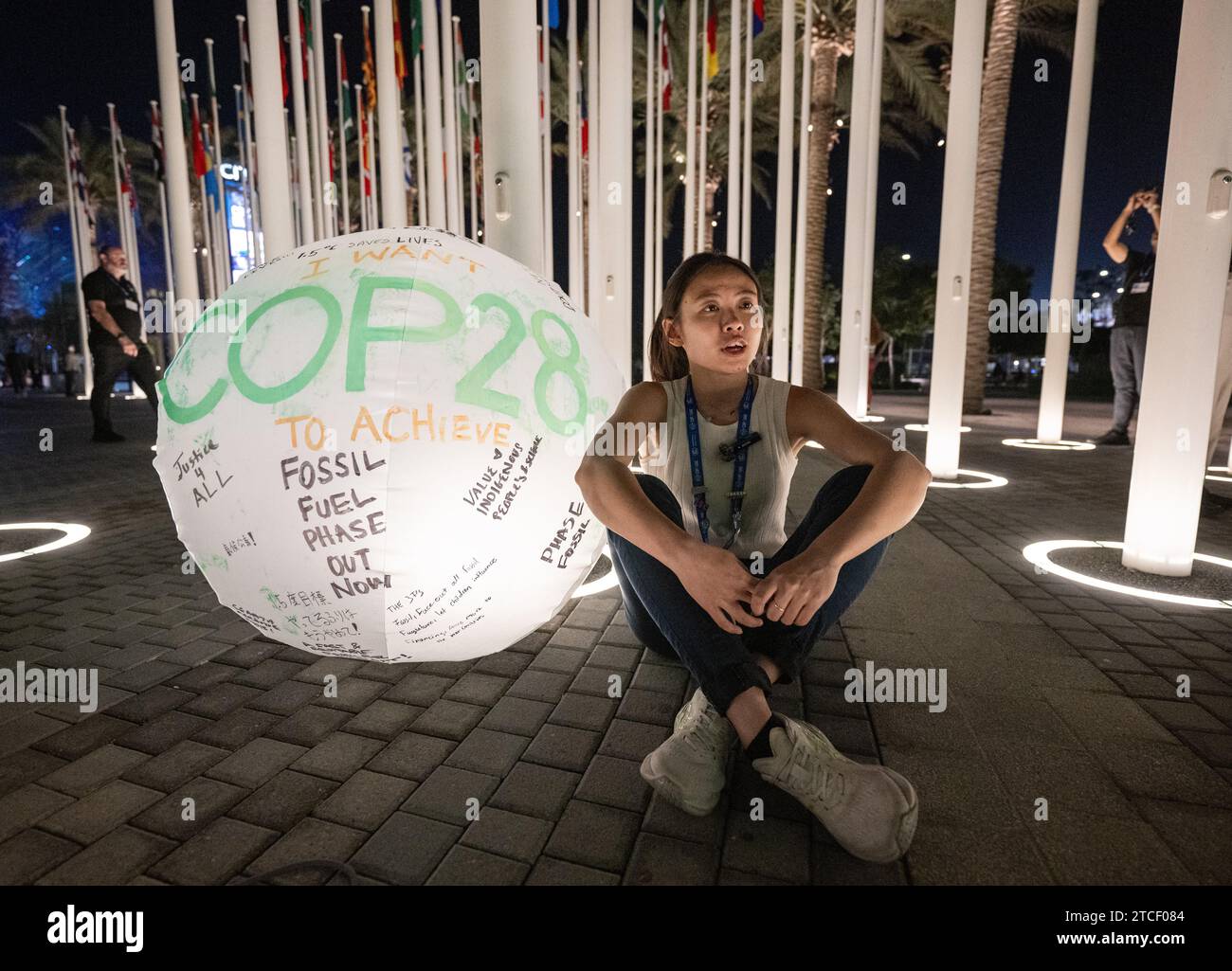 Dubai, Emirati Arabi Uniti. 12 dicembre 2023. Una donna siede accanto a un globo etichettato "COP28". La Conferenza mondiale sul clima è divenuta più lunga dopo una tempesta di proteste contro una bozza del testo finale. Credito: Hannes P. Albert/dpa/Alamy Live News Foto Stock