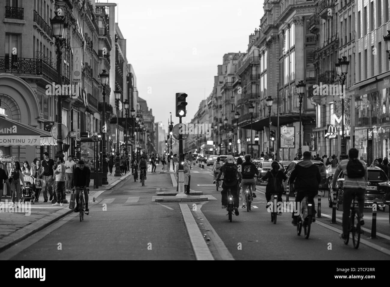 Parigi, Francia - 8 ottobre 2023: Veduta di pedoni, biciclette e auto nella trafficata Rue Rivoli, la strada commerciale di Parigi al tramonto Foto Stock