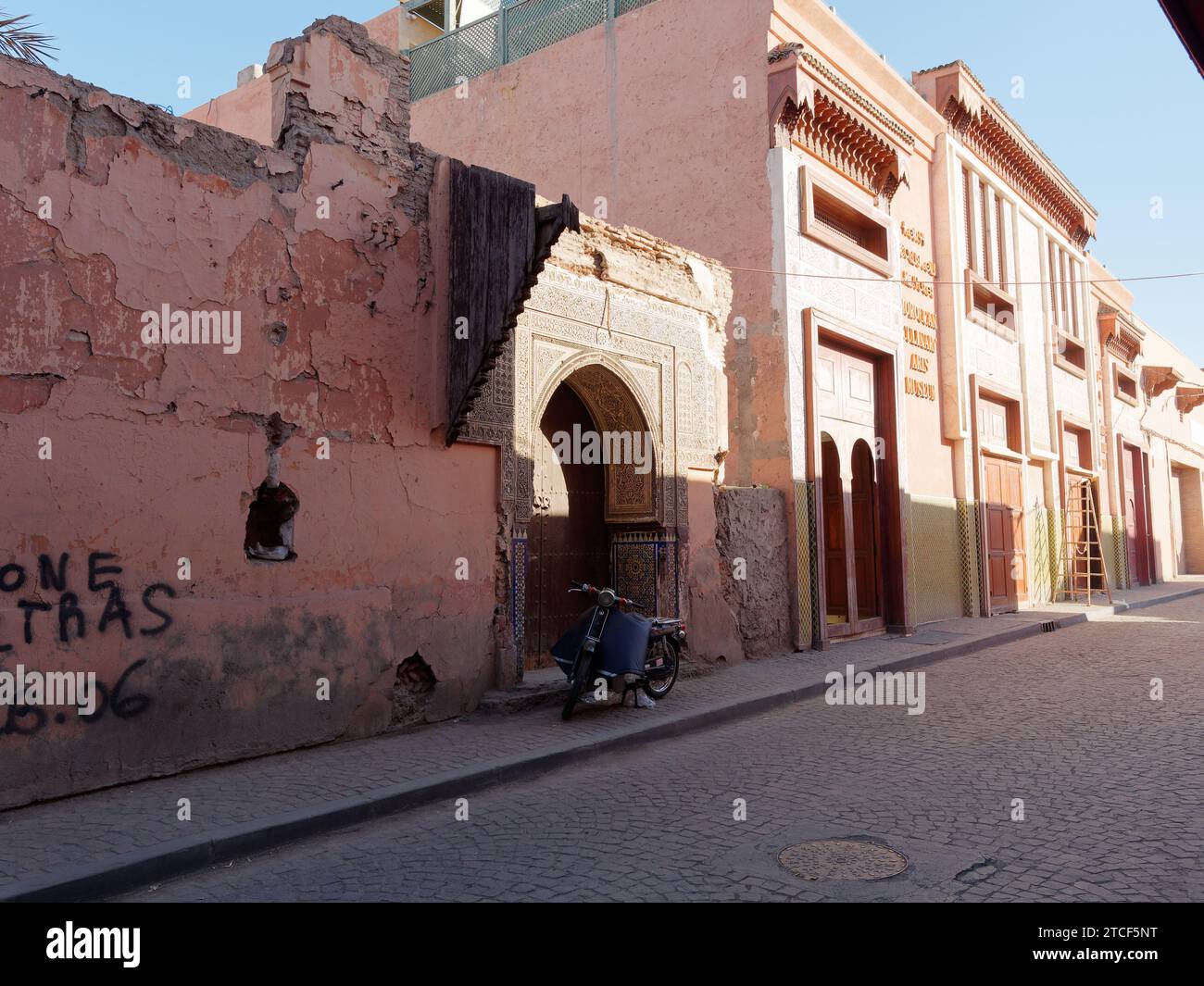 Edifici in argilla rossa e una moto nella Medina nella città di Marrakech, in Marocco, 12 dicembre 2023 Foto Stock