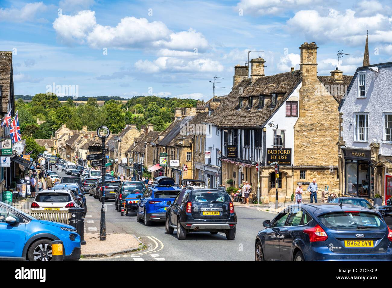 Ammira la trafficata Burford High Street (A361) dall'incrocio con Sheep Street a Burford, Oxfordshire, Inghilterra, Regno Unito Foto Stock