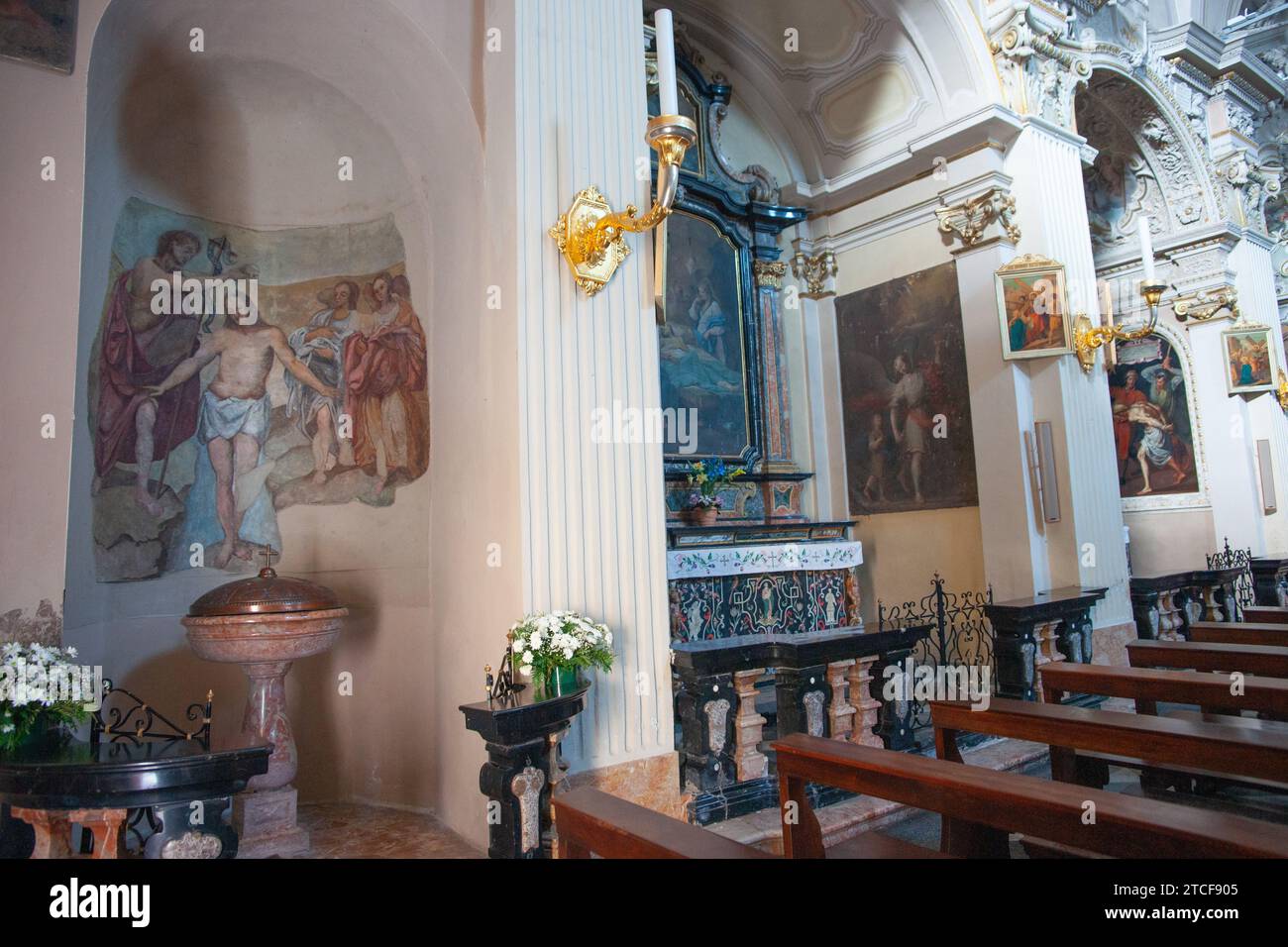 Menaggio, Italia, Grandola ed unità 7 maggio 2011; interni decorativi con fonte battesimale e altare laterale nella chiesa italiana - Chiesa di San Siro Codogn Foto Stock