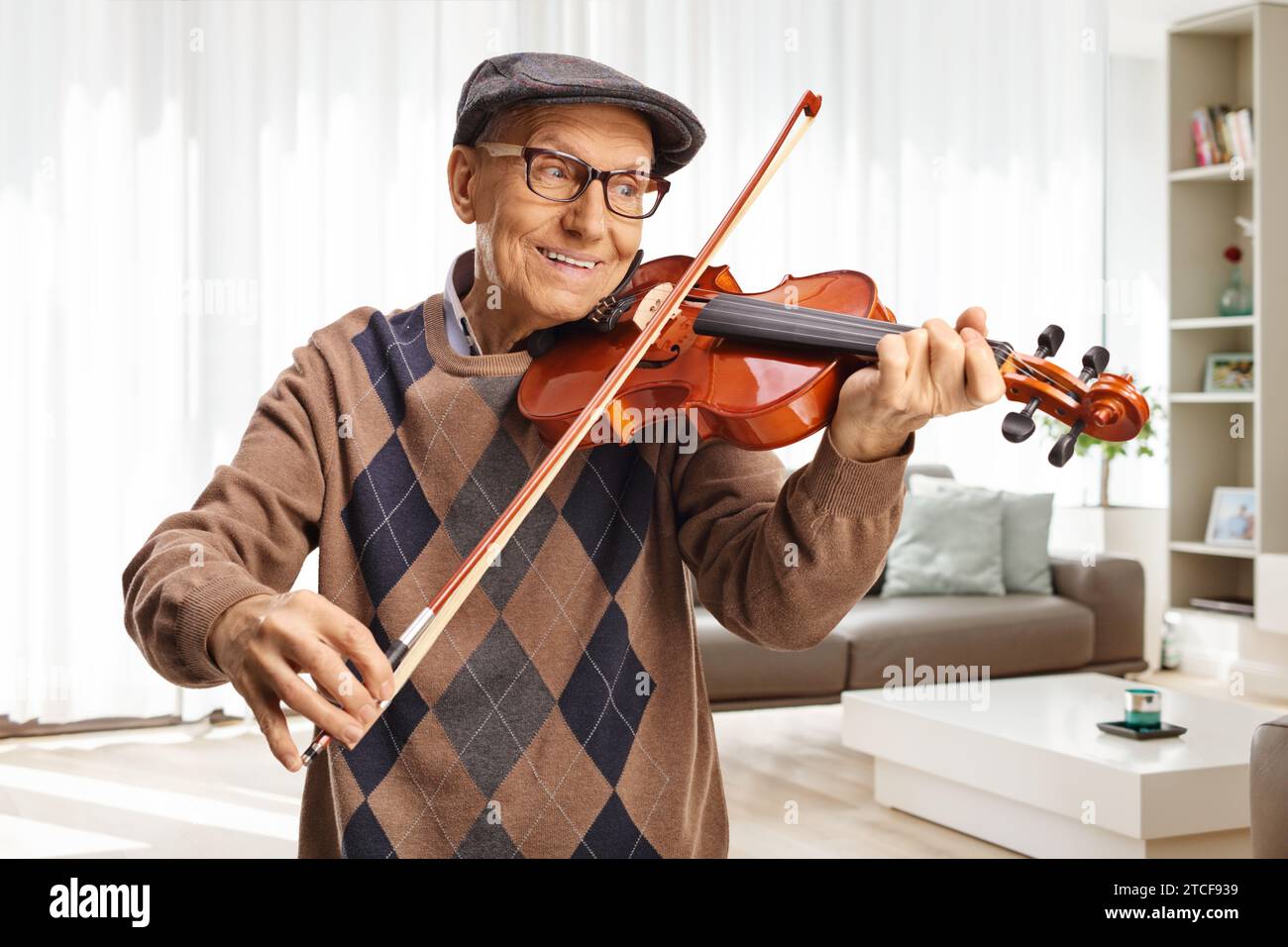 Felice pensionato che suona un violino a casa in salotto Foto Stock