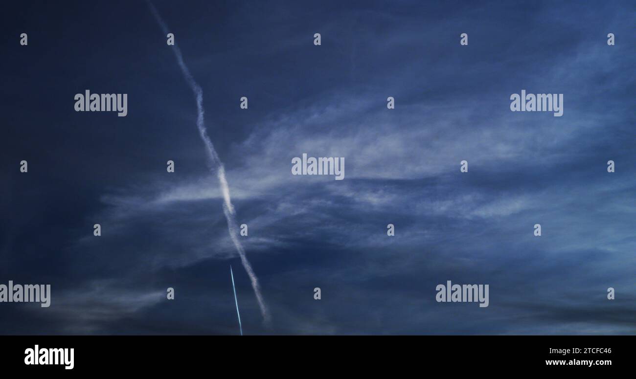 Il jet commerciale ad alta quota lascia una nuova e affilata contraglia lungo il percorso di un vecchio sentiero di condensazione persistente. Foto Stock