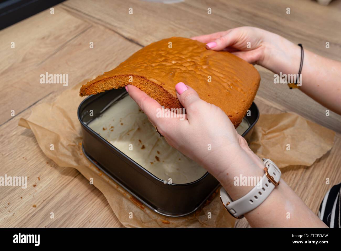 Preparazione di torta polacca, fudge con crema pasticcera, donna mette uno strato di torta. Foto Stock