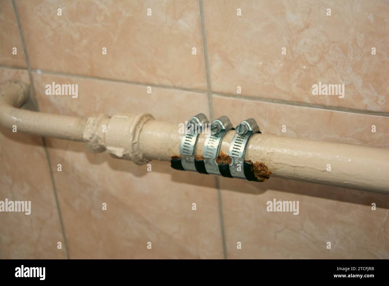 Primo piano di una riparazione idraulica improvvisata in un bagno in cui le bende sono avvolte intorno a un tubo di riscaldamento per fermare le perdite d'acqua, offrendo un'improvvisazione Foto Stock