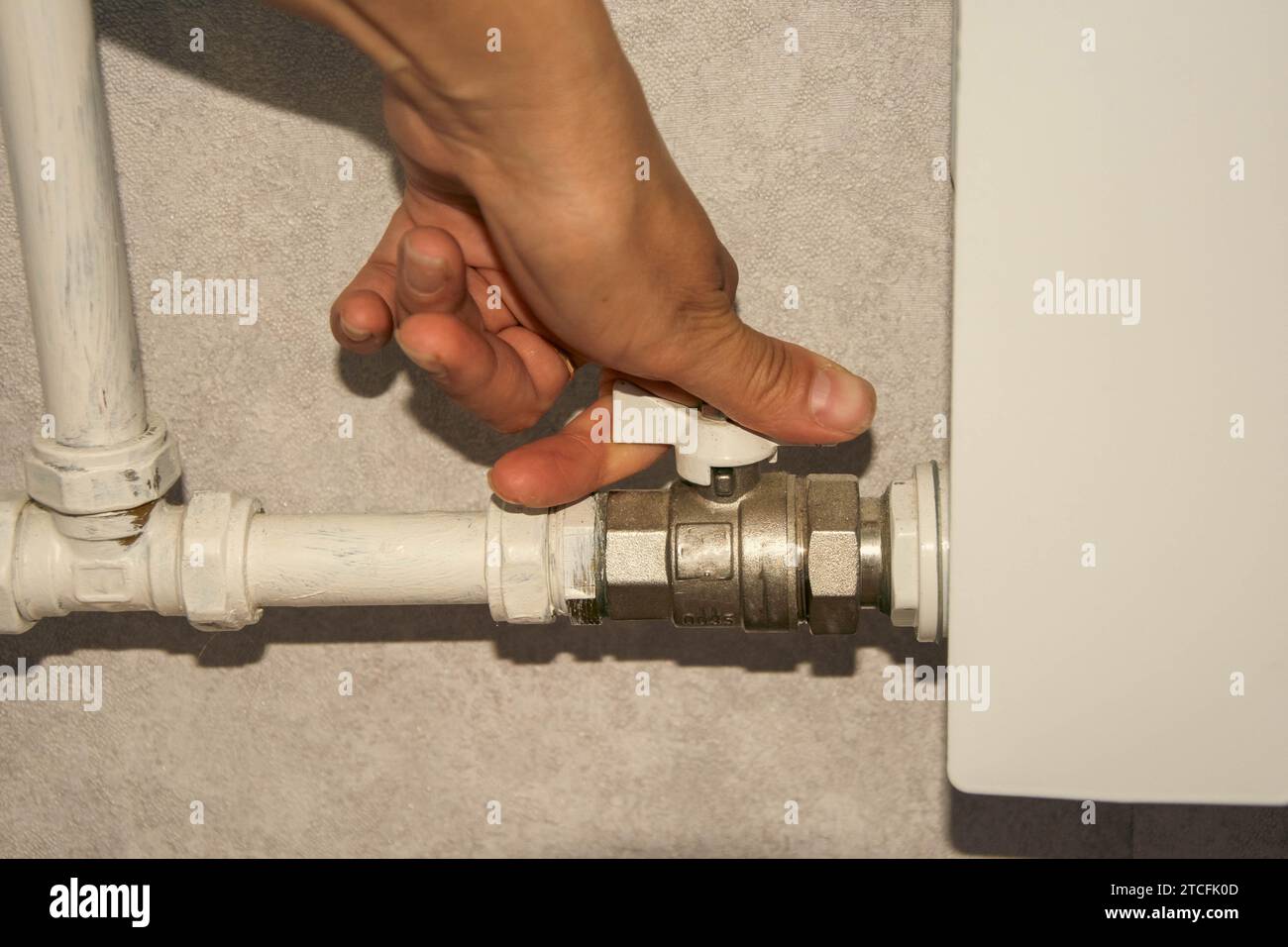 il proprietario chiude la valvola a sfera sul tubo di riscaldamento nell'appartamento. alimentazione termica alla batteria. Radiatore per riscaldamento in casa. Foto Stock
