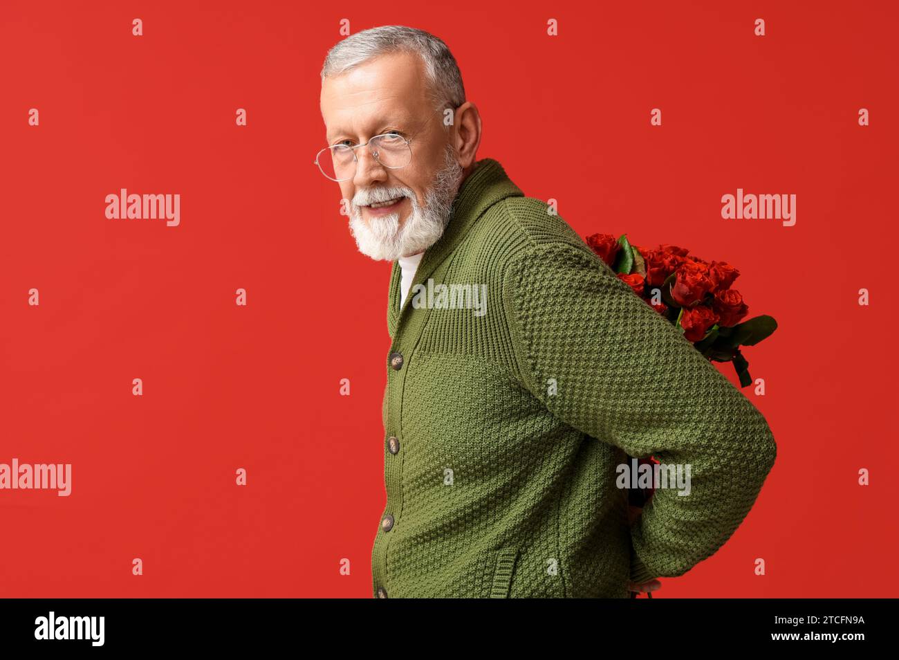 Uomo maturo con bouquet di rose su sfondo rosso. Festa di San Valentino Foto Stock