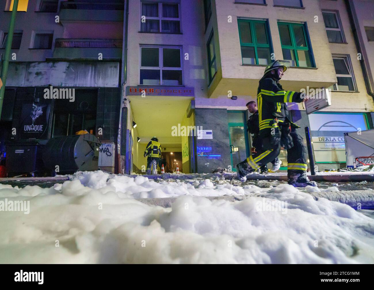Offenbach, Germania. 12 dicembre 2023. Una spessa coperta di schiuma copre la scena durante un'operazione di estinzione in un incendio in un edificio residenziale a tre piani. Secondo un portavoce dei vigili del fuoco, più di 30 persone vivono in casa. Credito: Andreas Arnold/dpa/Alamy Live News Foto Stock