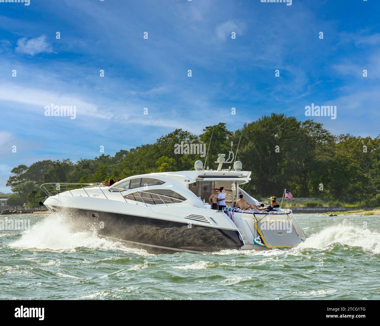 grande yacht a motore che ara nell'acqua con i passeggeri che si divertono Foto Stock
