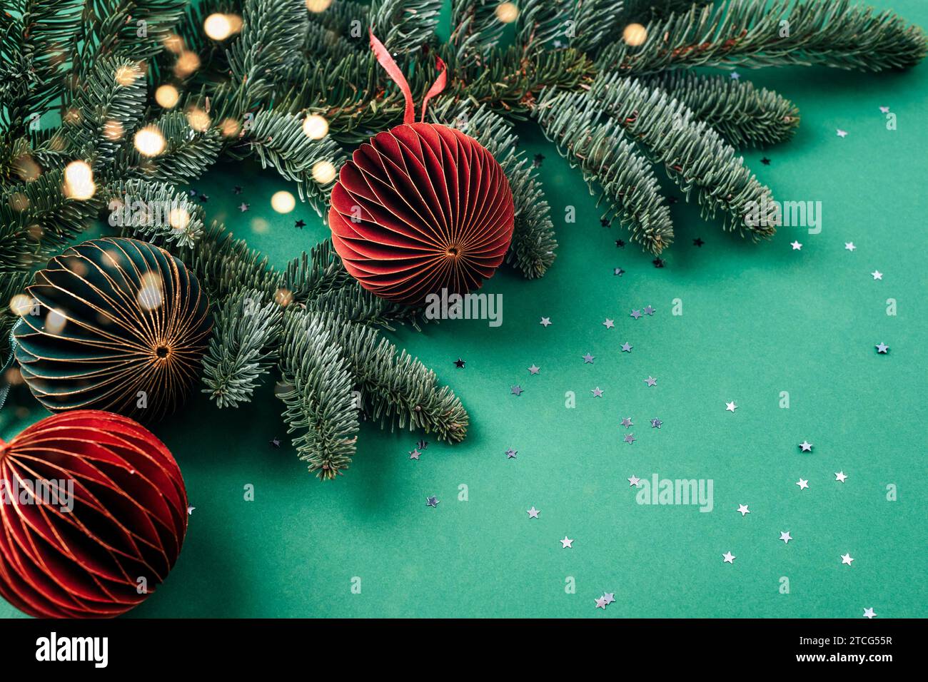 Giocattoli e rami di abete di carta con coriandoli dorati su sfondo verde. Concetto di Natale. Vista dall'alto, base piatta, spazio di copia. Foto Stock