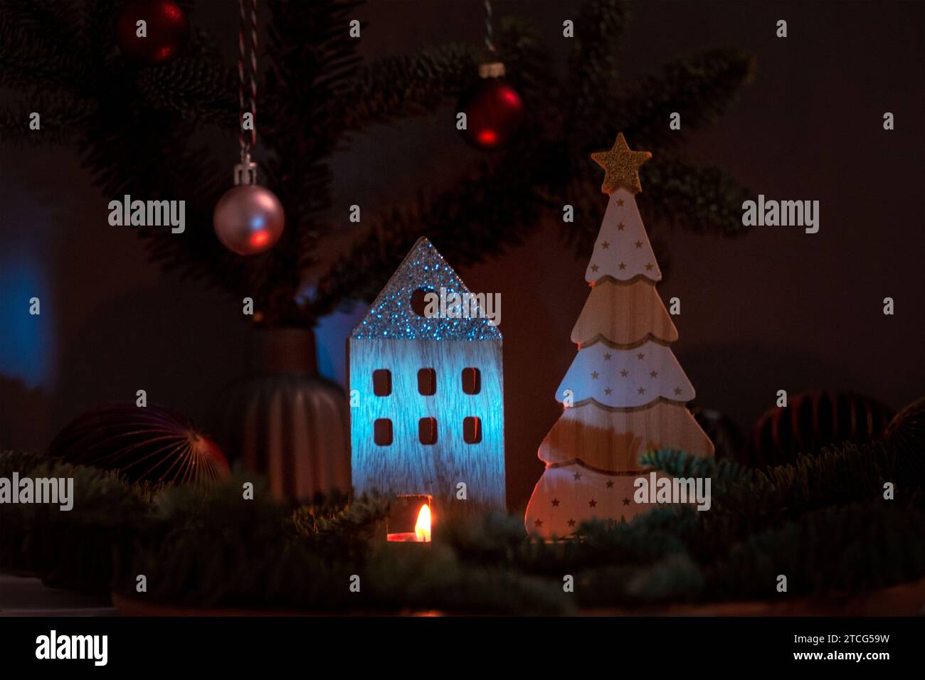Candele in fiamme e decorazioni natalizie in legno con rami di abete su sfondo scuro. Biglietto d'auguri per Natale o Capodanno. Foto Stock
