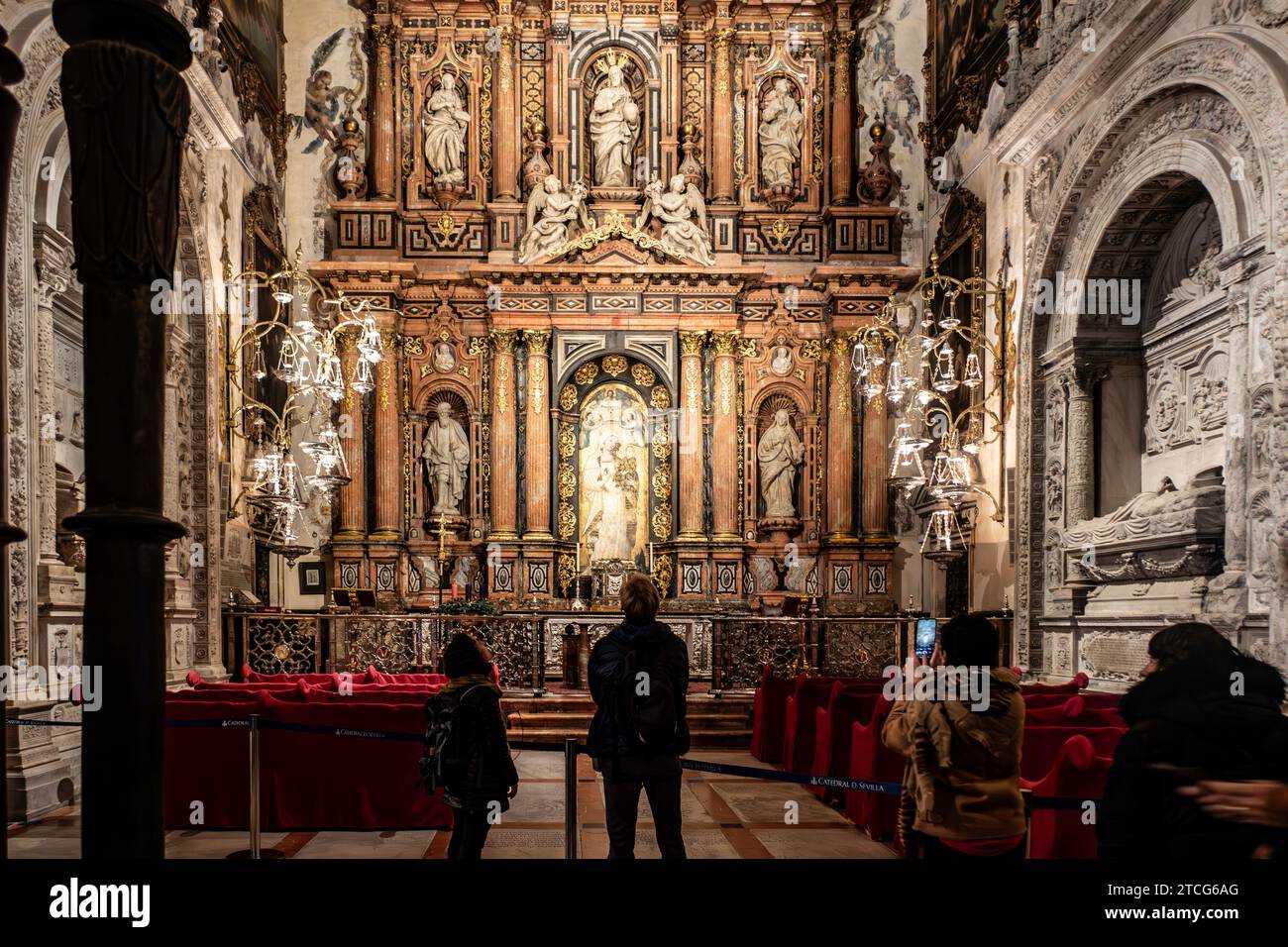 I turisti che guardano una dettagliata pala d'altare nella Cattedrale di Siviglia, in Spagna, un sito patrimonio dell'umanità dell'UNESCO Foto Stock