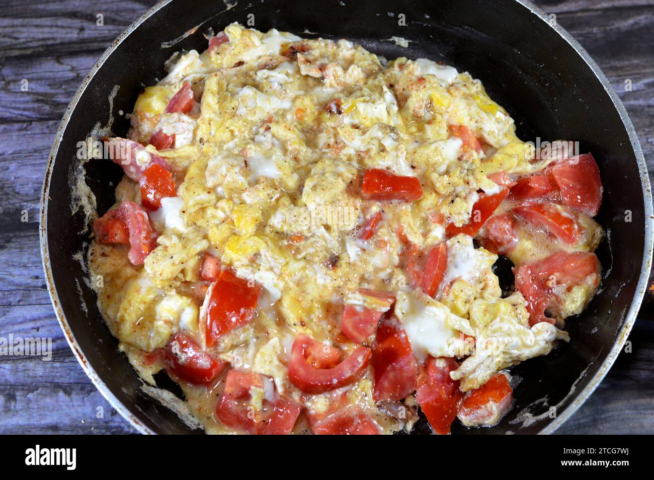 Uova strapazzate con pomodori, un piatto a base di uova mescolate, montate o sbattute insieme mentre vengono riscaldate delicatamente, con sale, burro, olio e pe nero Foto Stock