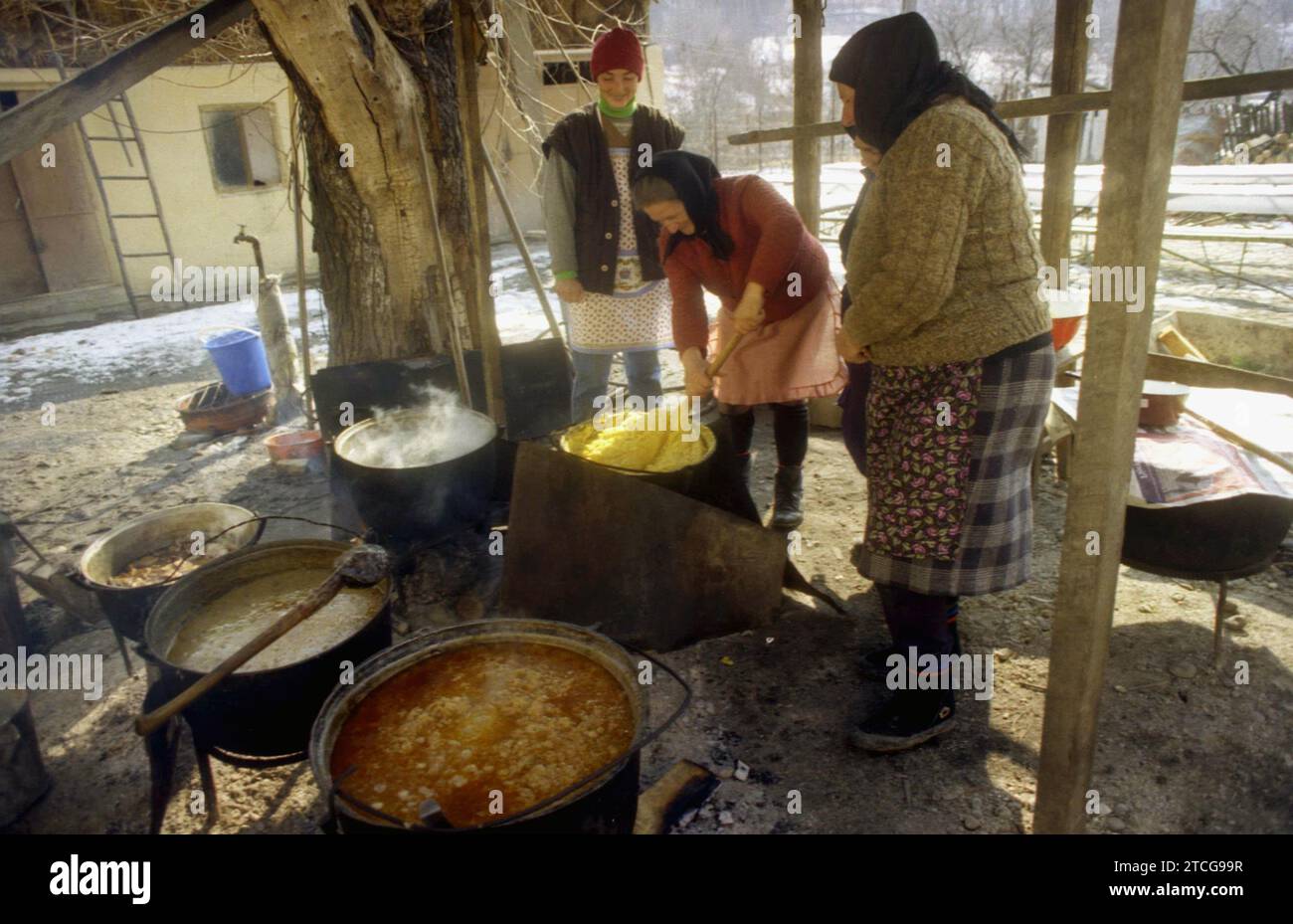 Tutana, Contea di Arges, Romania, 2000. Donne che preparano cibo tradizionale fuori, sopra il fuoco, in grandi calderoni, per un evento nel villaggio. Foto Stock