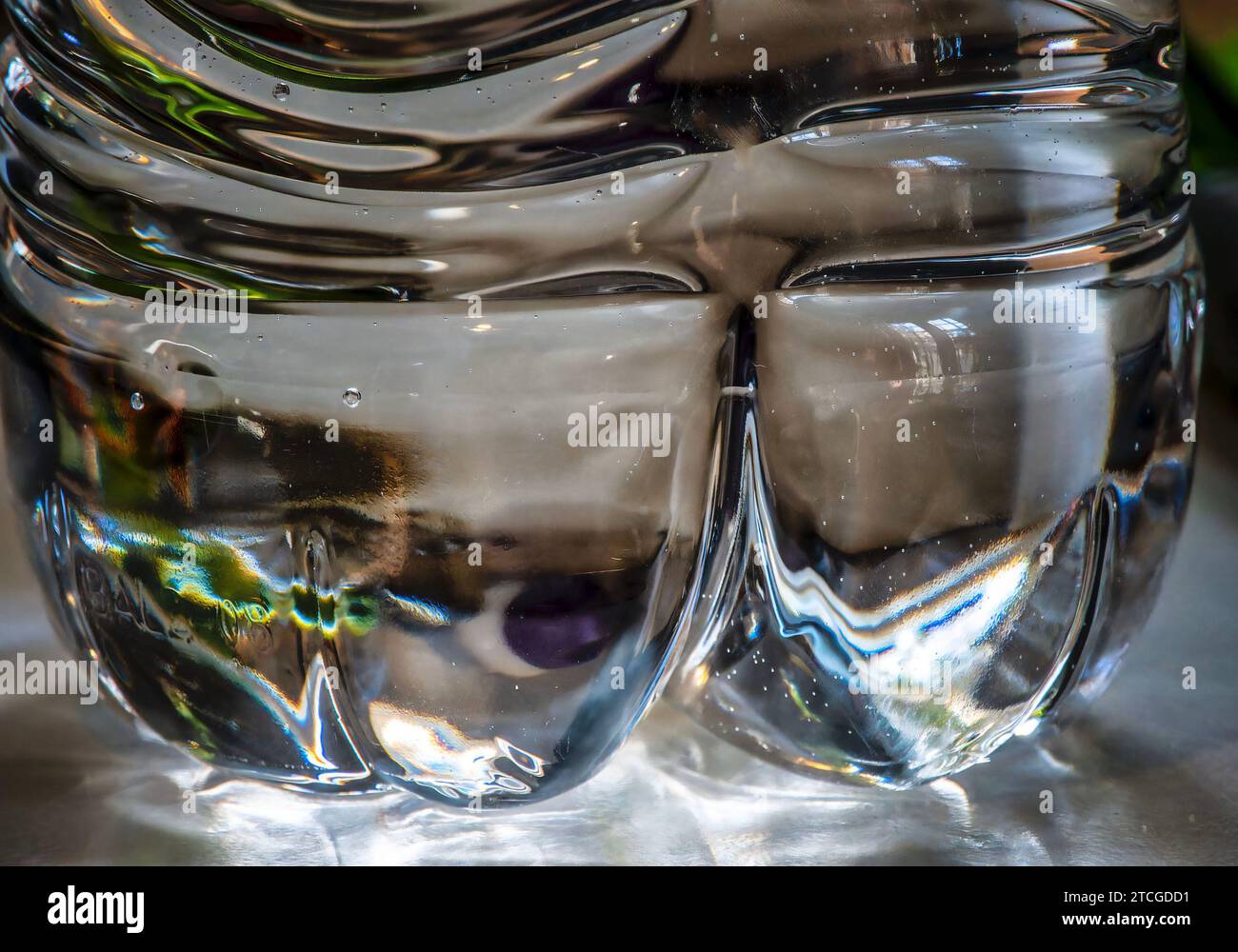 Parte inferiore di una bottiglia d'acqua in plastica nella luce della finestra Foto Stock