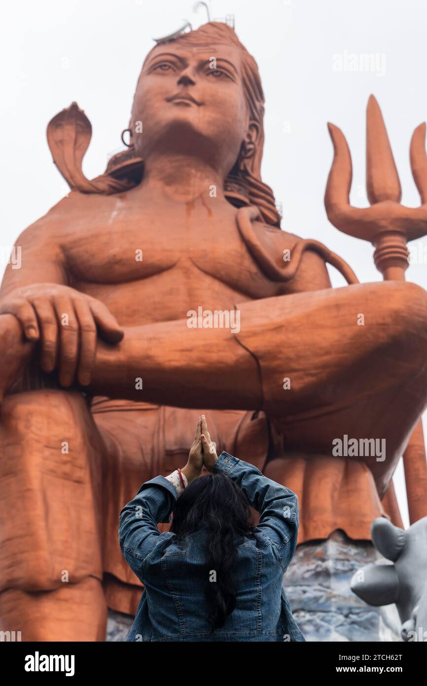 Giovane ragazza che paga il saluto alla statua del dio indù shiva al mattino da un'immagine ad angolo piatto viene scattata alla Statua della credenza o Vishwas Swaroopam nat Foto Stock