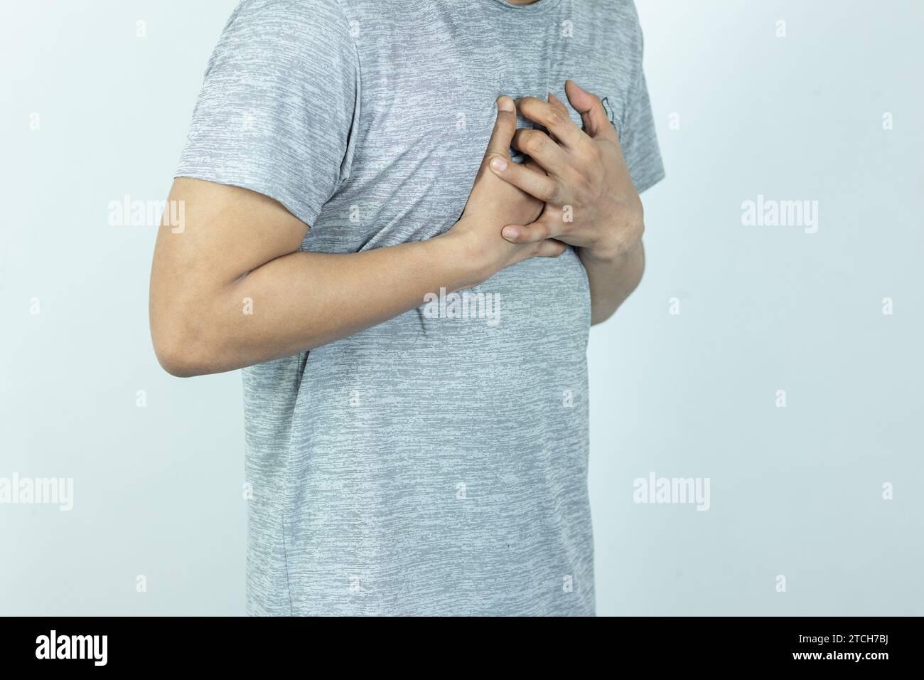 uomo asiatico che preme il petto con espressione dolorosa. Dolore grave, con attacco di cuore o crampi dolorosi, malattie cardiache. Foto Stock