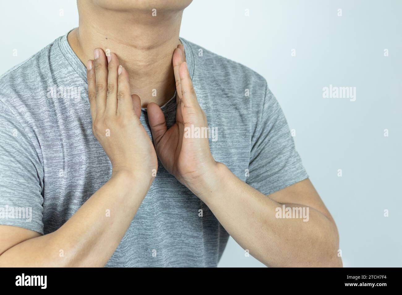 Uomo asiatico che tocca il collo con la mano perché soffre di mal di gola Foto Stock