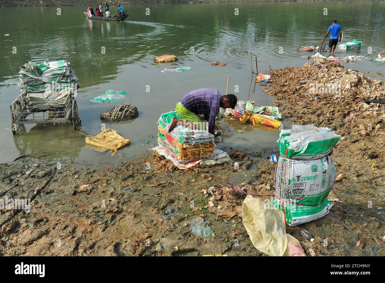 Le donne rischiano la vita per lavare sacchi di cemento vicino al fiume Surma a Sylhet. È dannoso per la loro salute, e la polvere di plastica riempie anche il letto del fiume che danneggia l'ambiente. L'esposizione ad alti livelli di polvere di cemento irrita il naso e la gola, con conseguente rischio di asma professionale e altre malattie. La Malta può anche contenere silice cristallina respirabile (RCS), che si trova anche nel calcestruzzo e può portare allo sviluppo di silicosi o cicatrici dei polmoni, con conseguente perdita della funzionalità polmonare e grave mancanza di respiro. Sylhet, Bangladesh. Foto Stock