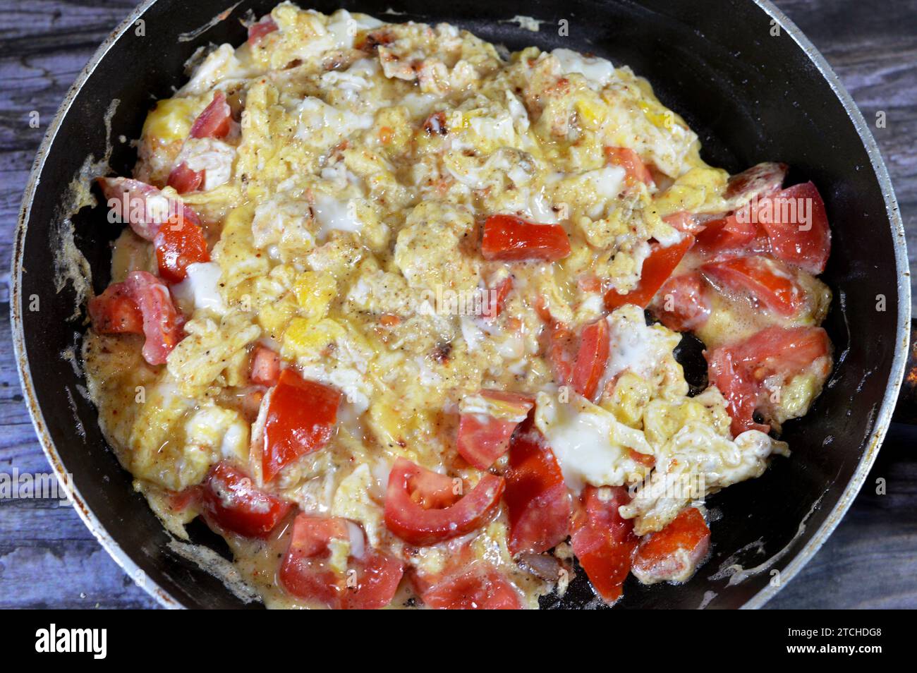 Uova strapazzate con pomodori, un piatto a base di uova mescolate, montate o sbattute insieme mentre vengono riscaldate delicatamente, con sale, burro, olio e pe nero Foto Stock