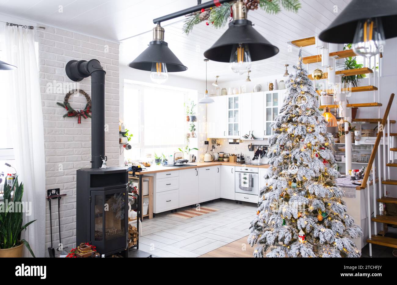 Decorazioni natalizie natalizie in cucina bianca, interni rustici moderni con un albero di Natale innevato e luci delle fate. Capodanno, atmosfera natalizia, casa accogliente. TH Foto Stock