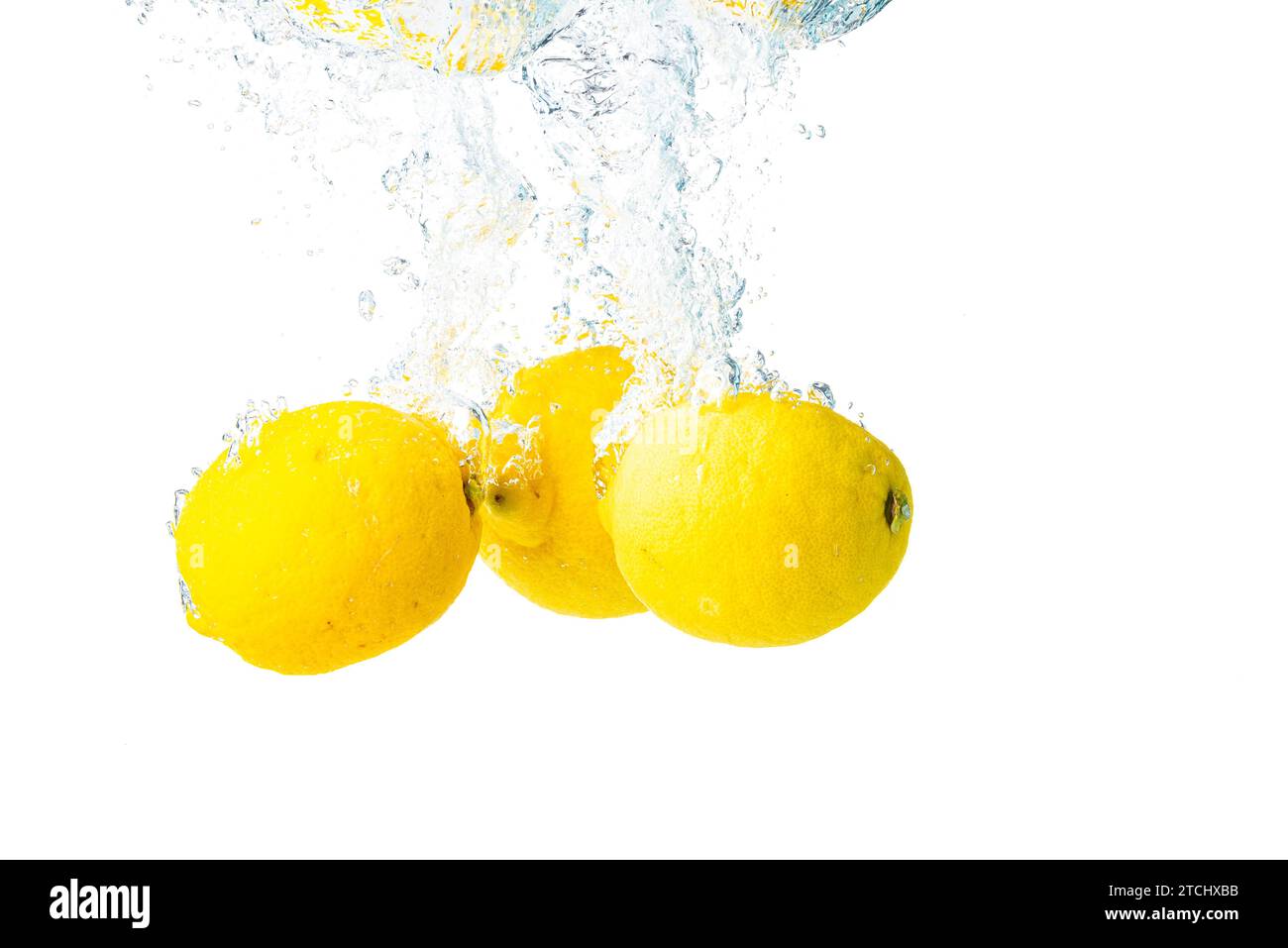 I limoni si tuffano in acqua e affondano su sfondo bianco. Cibo gustoso e sano Foto Stock