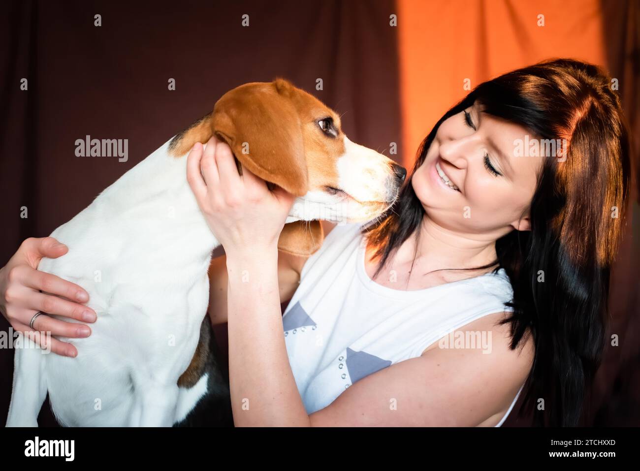 Giovane donna coccola con il cane Beagle in interni luminosi. Concetto PET Friendship Foto Stock