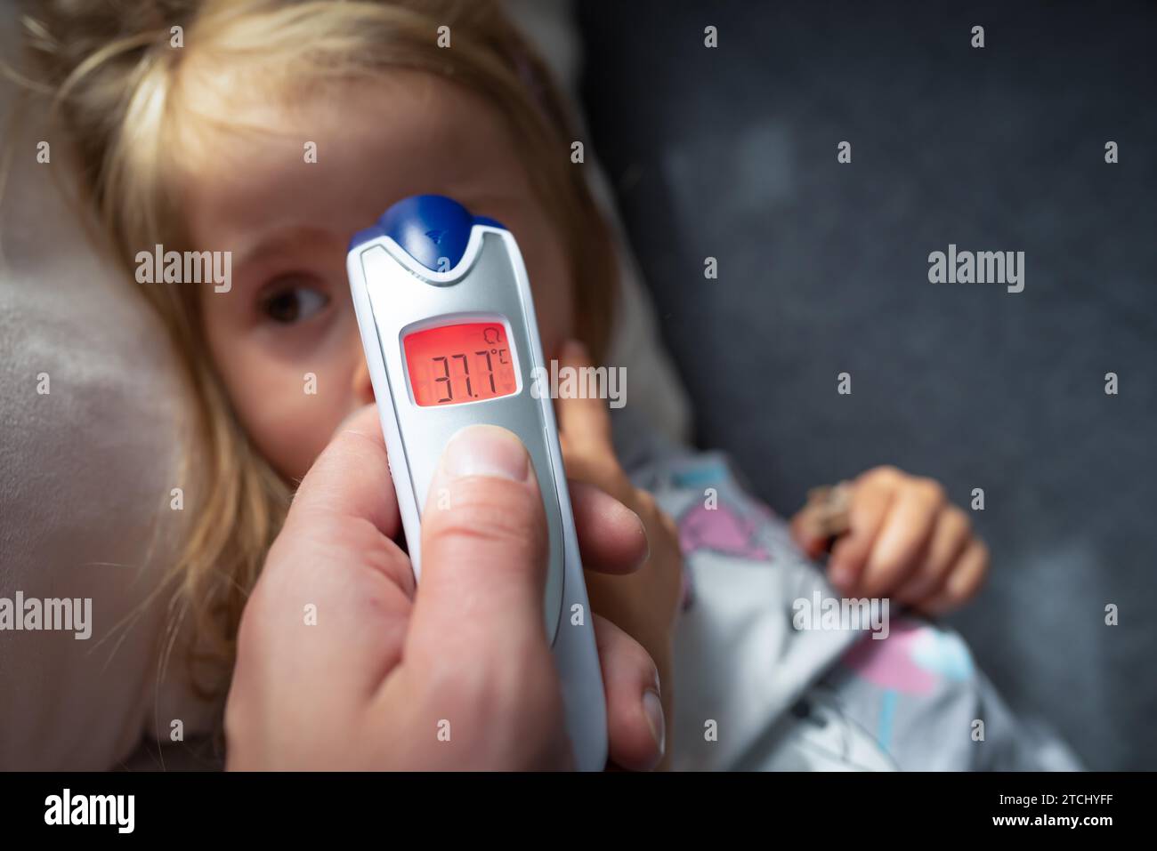 La madre prende la temperatura per il suo bambino con il termometro a infrarossi a casa, il termometro digitale a infrarossi per la mano della madre Foto Stock