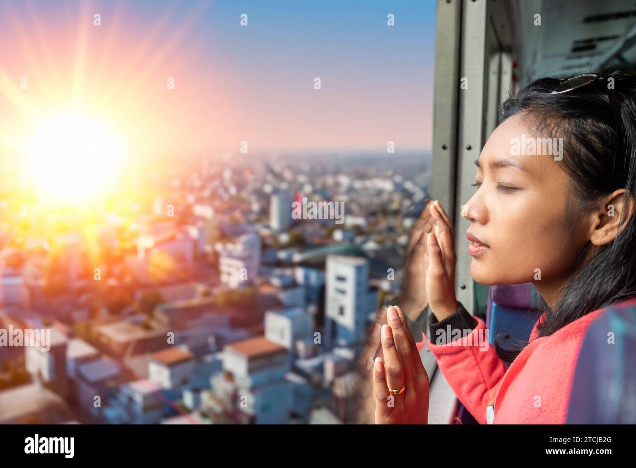 Una giovane donna guarda la città illuminata dal sole da un autobus in movimento Foto Stock