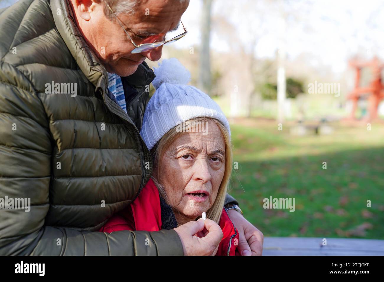 Un uomo che dà la pillola medica a una donna paziente con bipolarità o schizofrenia fuori. Concetto di trattamento della salute mentale Foto Stock