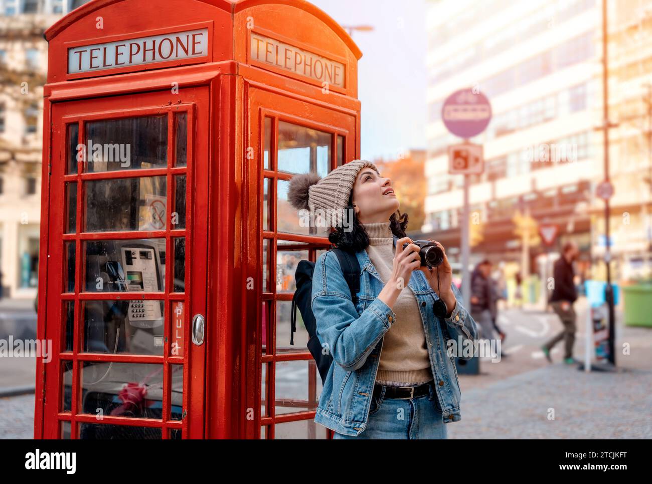 Ritratto all'aperto di una donna che usa la fotocamera contro una scatola telefonica rossa in una città inglese Foto Stock