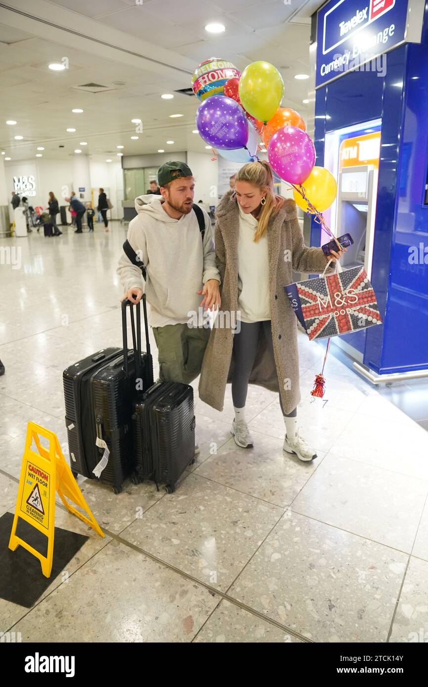Il vincitore della serie Sam Thompson (a sinistra) viene accolto da Zara McDermott all'aeroporto di Heathrow, Londra, dopo aver preso parte alla serie ITV i'm A Celebrity Get me Out of Here! In Australia. Data foto: Mercoledì 13 dicembre 2023. Foto Stock