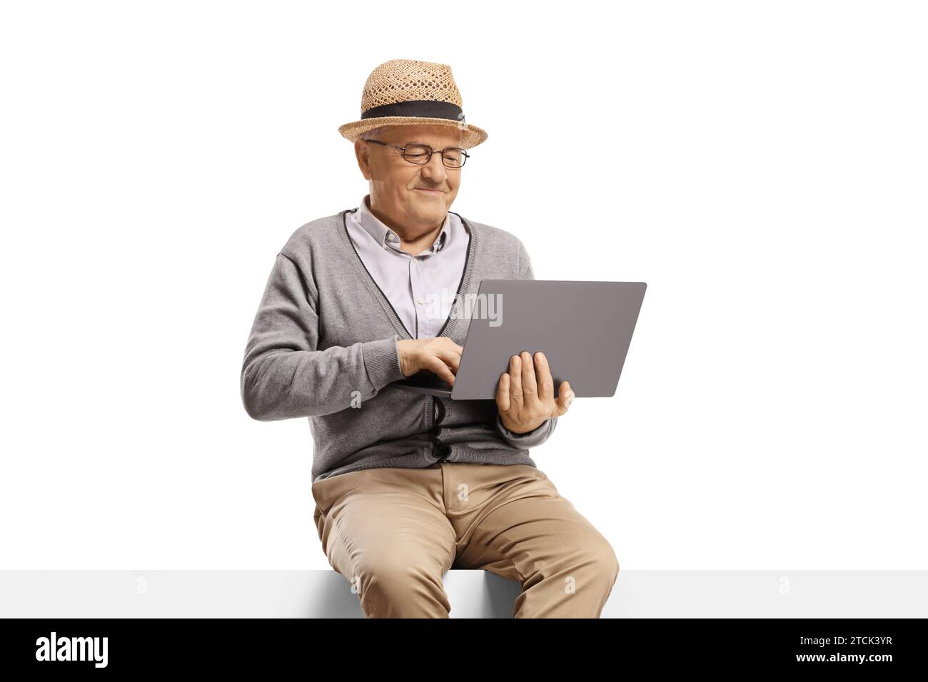 Uomo anziano seduto su un pannello vuoto e che utilizza un computer portatile, generazioni più vecchie e concetto tecnologico Foto Stock