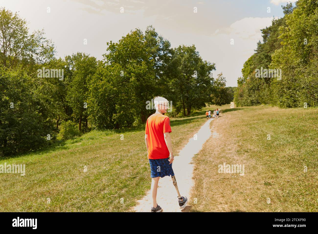 Ragazzo con gamba protesica che cammina lungo il sentiero del parco Foto Stock