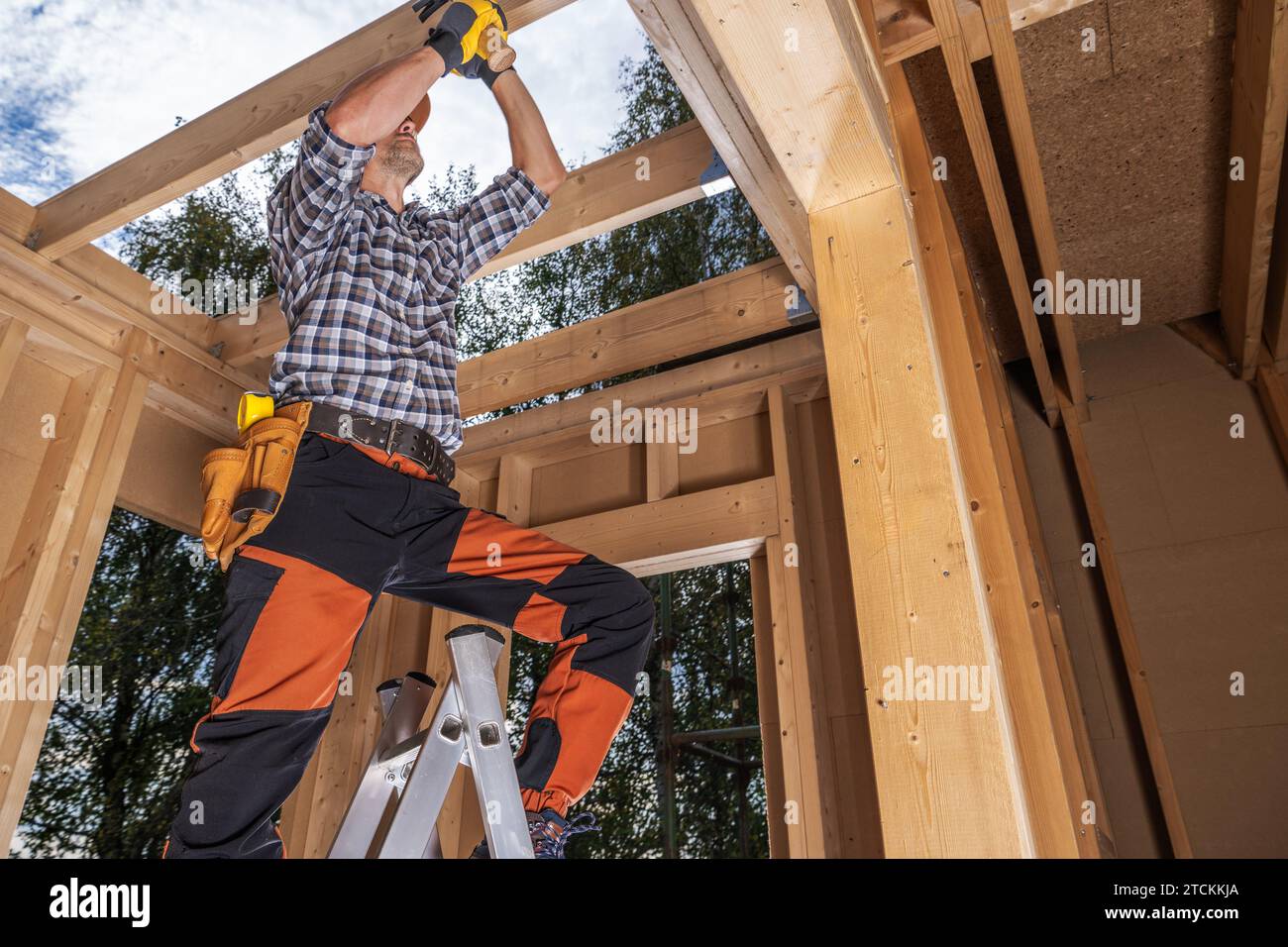 Costruzione di strutture in legno. Operaio appaltatore caucasico che assembla elementi in legno Foto Stock