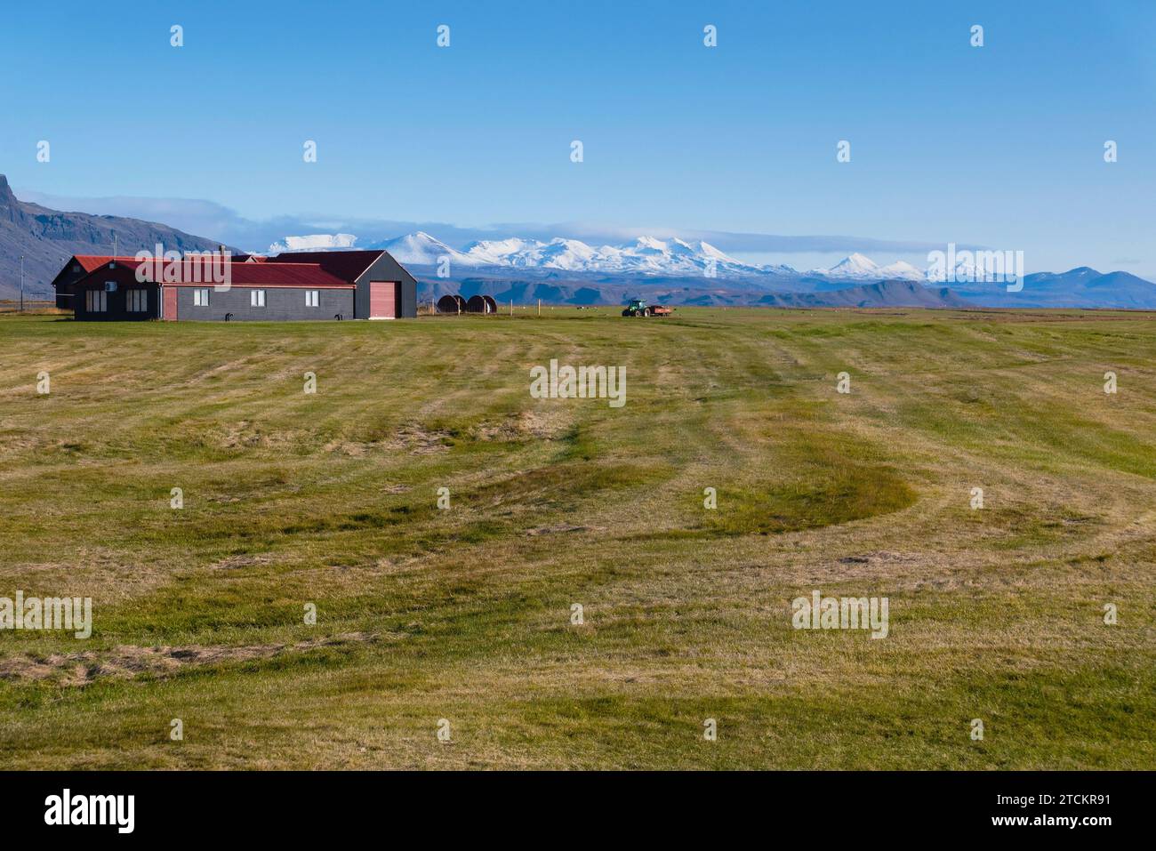 Islanda, Parco Nazionale della Penisola di Snæfellsnes, azienda agricola e campi. Con montagne innevate in lontananza. Foto Stock