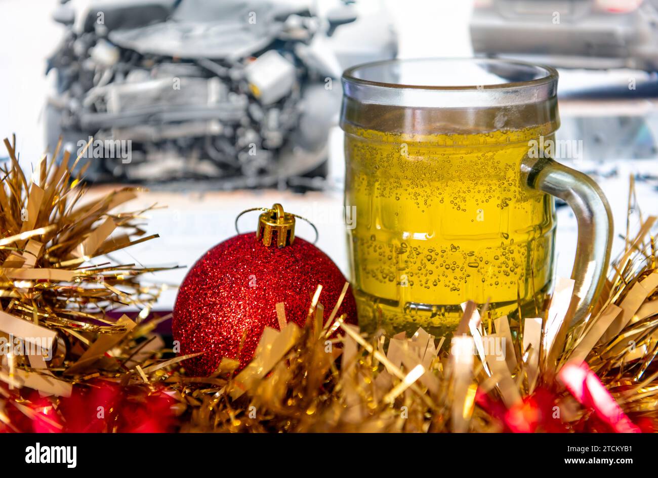 Un concetto di guida con bevande natalizie con una pinta di birra e decorazioni natalizie con un'immagine di un'auto che si è rotta sullo sfondo. Foto Stock