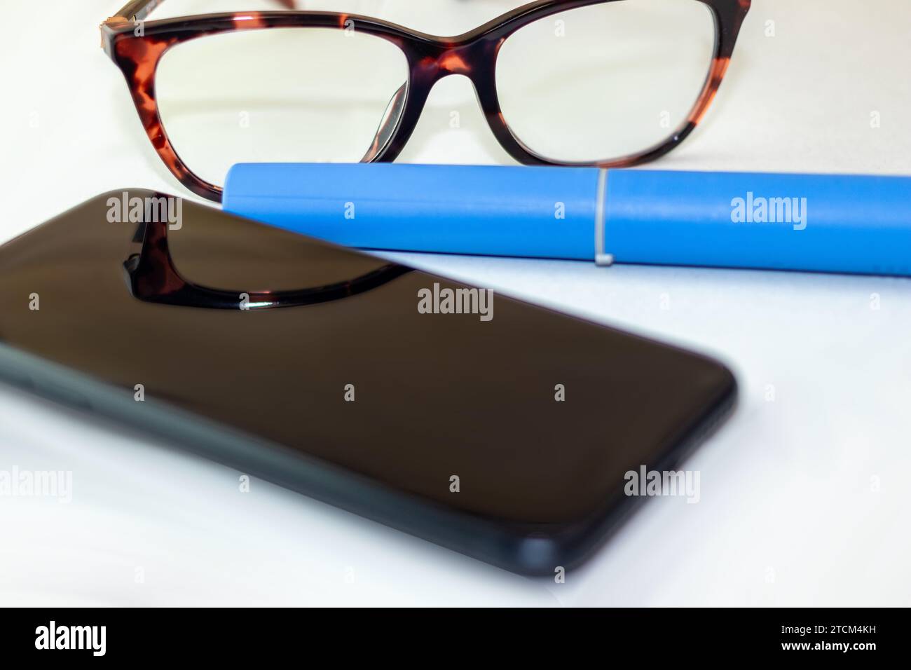 Concetto di farmacia online che mostra il telefono cellulare, la penna semaglutide e gli occhiali sulla scrivania Foto Stock
