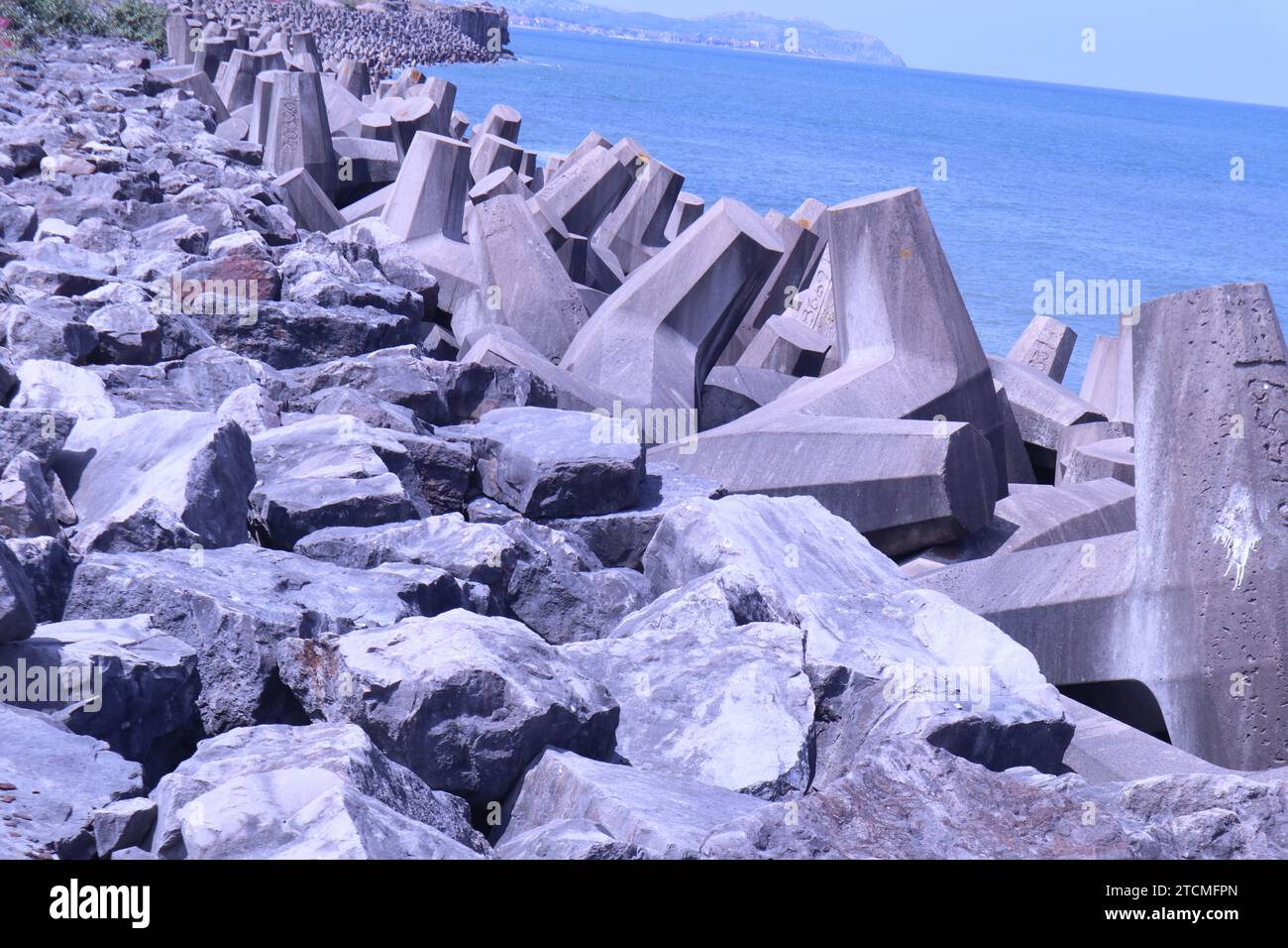 Penrhyn Bay, Galles, Regno Unito 7 giugno 2023 strutture in cemento schierate lungo l'area di Colwyn Bay che hanno progettato di bloccare e fornire una barriera difensiva contro le onde e proteggere la costa. I blocchi sono stati progettati con un motivo a T in modo che, anziché essere spazzati via individualmente, si interfacciano per fornire una barricata di roccia e un muro di breeakwall ©Ged Noonan/Alamy Foto Stock