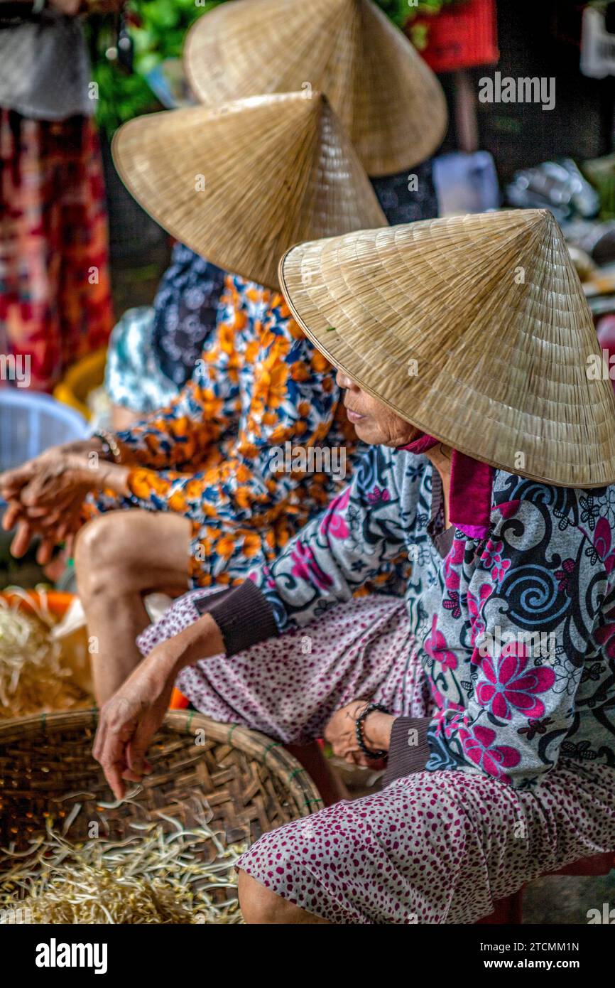 Donne che indossano tradizionali cappelli di paglia - non la - a Hoi An Market, Vietnam Foto Stock