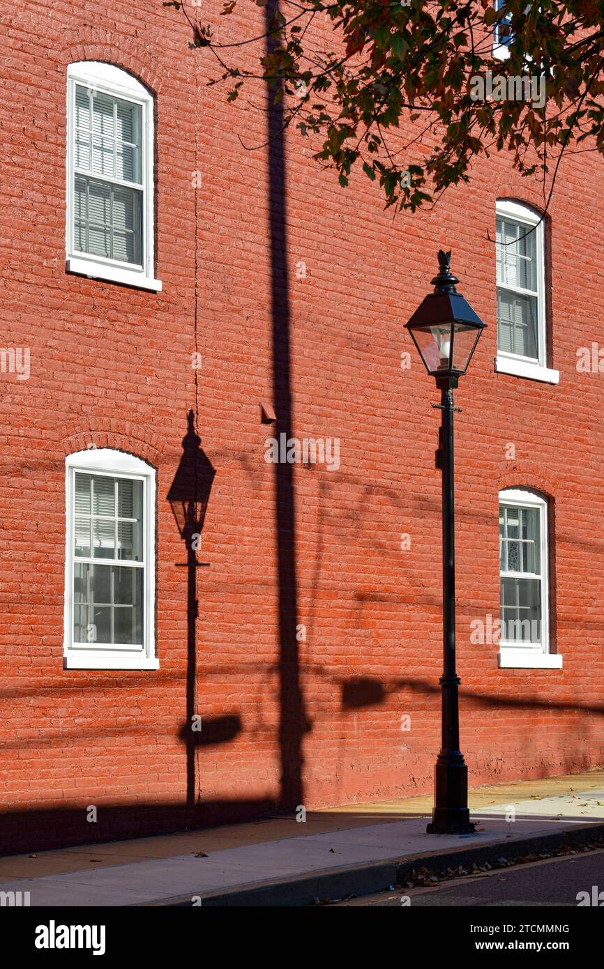 Ombra di una lampada a gas su un muro dipinto di rosso in Frederick Street, nel quartiere storico di Fredericksburg, Virginia Foto Stock