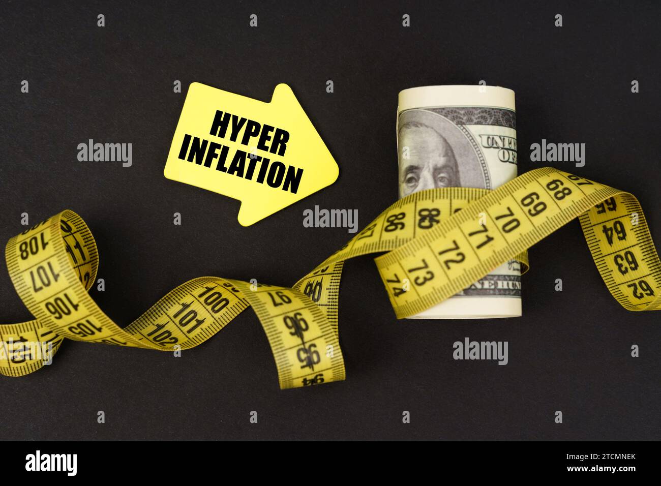 Concetto aziendale. Su una superficie nera ci sono dei dollari avvolti in un metro a nastro e adesivi con l'iscrizione - Hyper Inflation Foto Stock