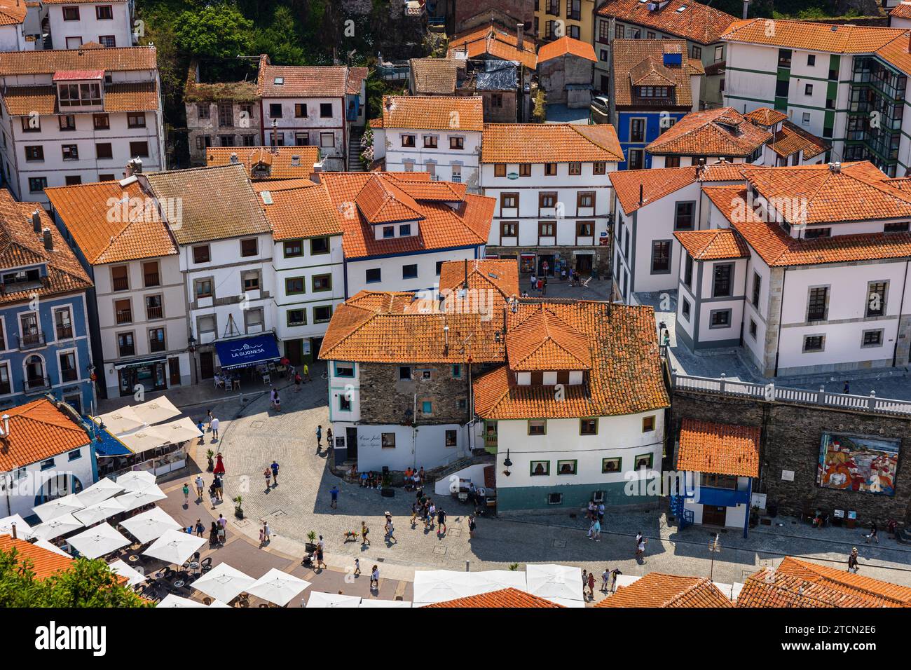 Vista ravvicinata della piazza principale della città, dei ristoranti, delle case bianche con tetti di tegole rosse. Giornata di sole. Cudillero, Asturie, Spagna. Foto Stock