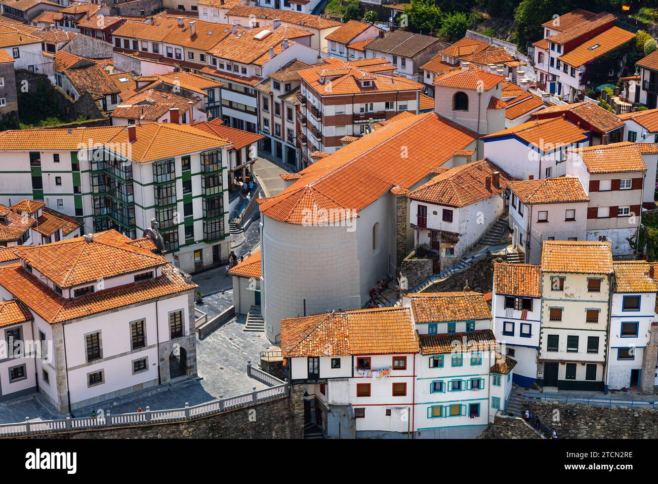 Vista ravvicinata della chiesa della città e delle strade centrali circostanti, case bianche con tetti di tegole rosse. Giornata di sole. Cudillero, Asturie, Spagna. Foto Stock