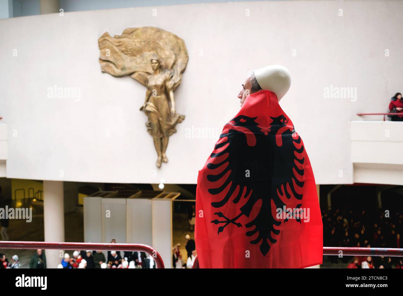 Tirana, Albania - novembre 28: Un uomo drappeggiato con la bandiera albanese si affaccia sulla statua di madre Teresa, in mezzo alle celebrazioni del giorno dell'indipendenza Foto Stock