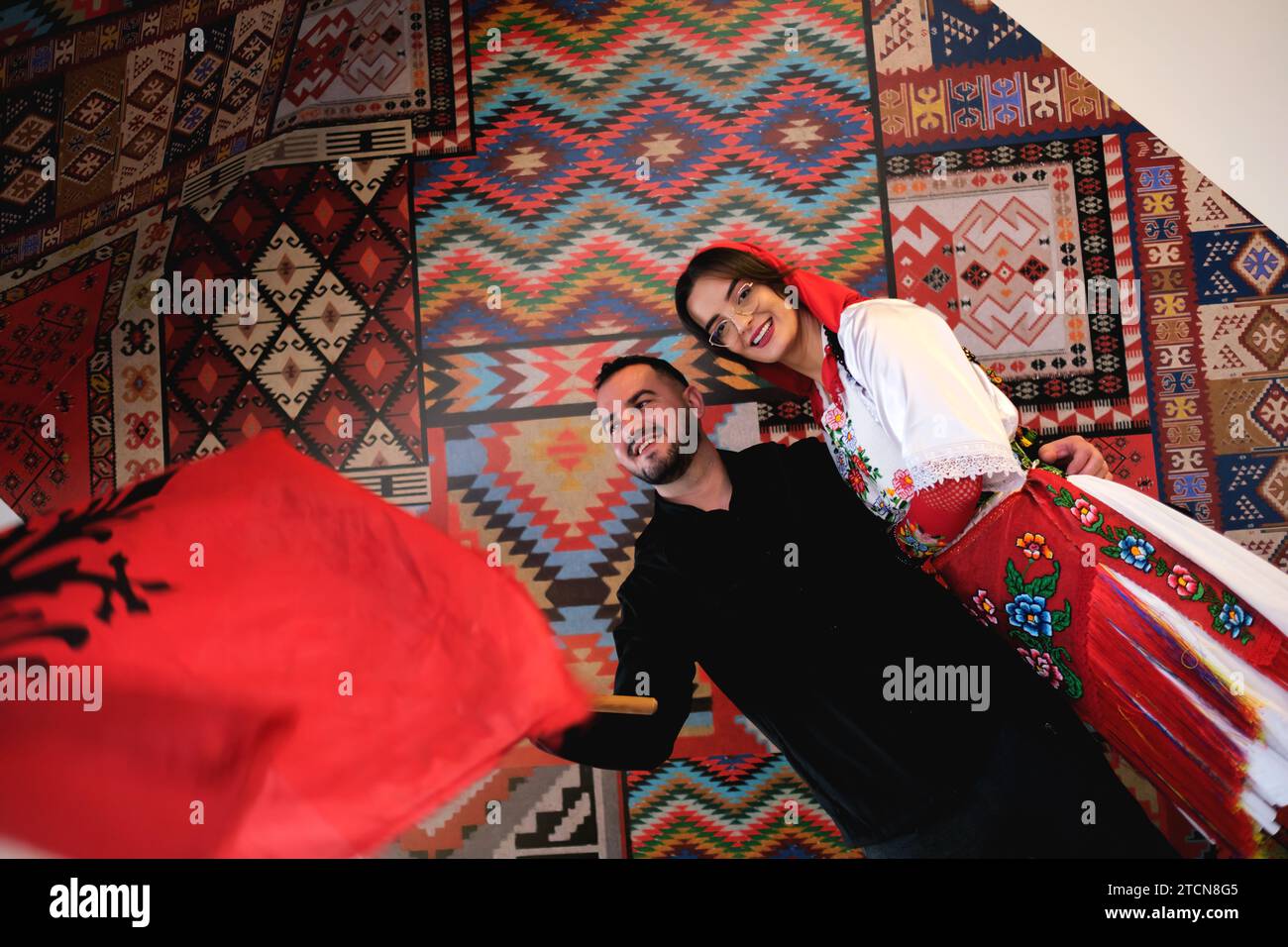 Tirana, Albania - novembre 28: Una donna e un uomo in abiti tradizionali albanesi, in posa con una bandiera davanti a modelli tradizionali Foto Stock