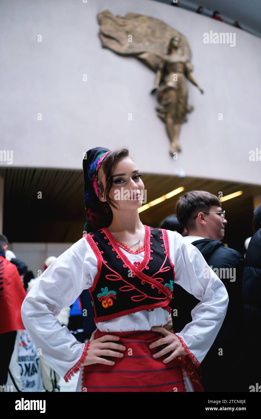 Tirana, Albania - novembre 28: Una studentessa in tradizionale abbigliamento albanese posa di fronte alla statua di madre Teresa al Palazzo Foto Stock