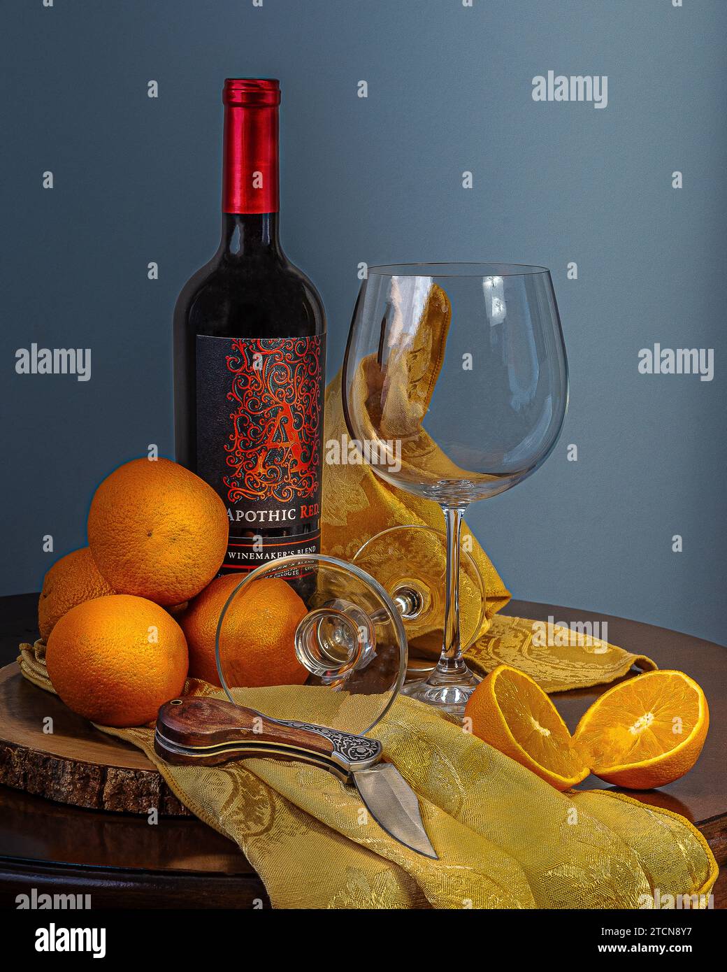 Foto natura morta. Una foto scura e suggestiva di una natura morta, una bottiglia di vino, bicchieri, arance. Foto Stock