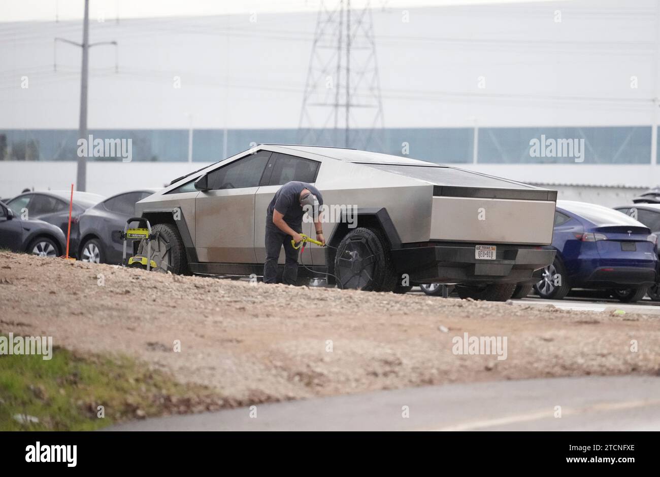 Austin, Texas, USA. 13 dicembre 2023. Un lavoratore lava un nuovo Tesla Cybertruck parcheggiato fuori dall'enorme fabbrica Tesla nel sud-est di Austin mentre i lavoratori controllano le attrezzature e le allontanano, due settimane dopo aver consegnato i primi modelli agli acquirenti VIP in una cerimonia privata. È in corso una massiccia espansione presso lo stabilimento Tesla in Texas, con la costruzione di diversi nuovi edifici. (Immagine di credito: © Bob Daemmrich/ZUMA Press Wire) SOLO USO EDITORIALE! Non per USO commerciale! Foto Stock