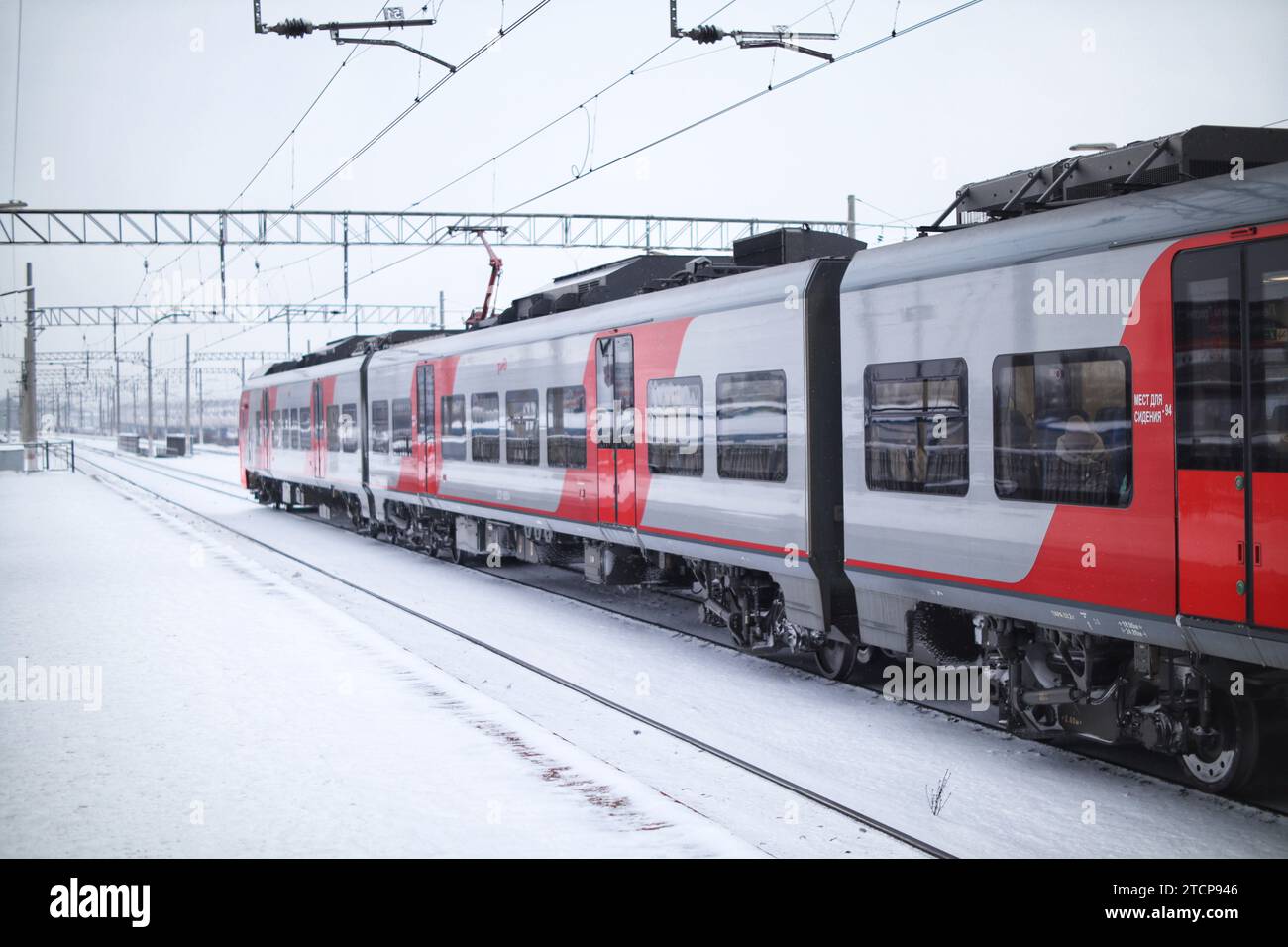 Un treno elettrico che parte dalla stazione in un giorno d'inverno Foto Stock